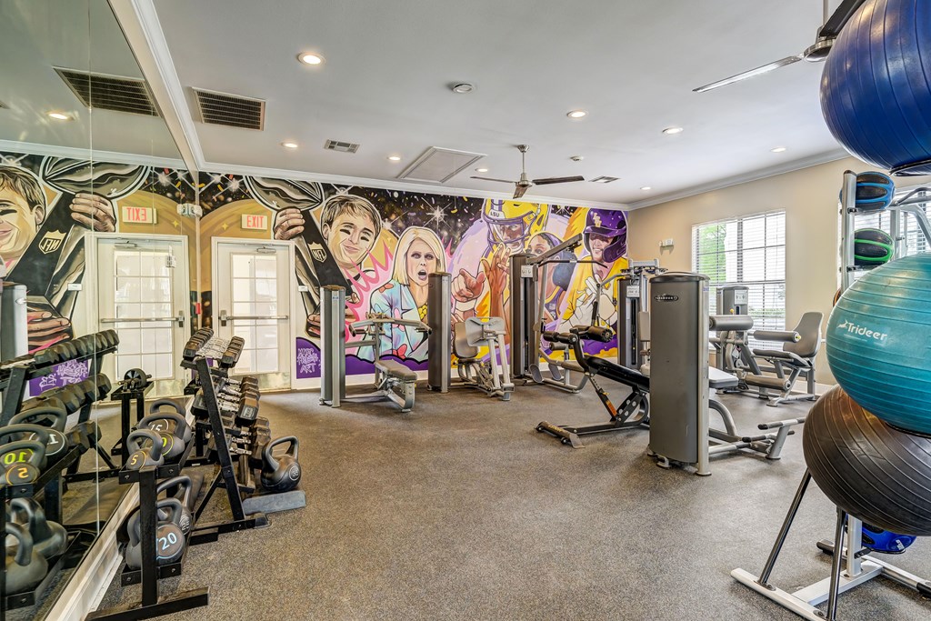 A gym with a variety of equipment including weights and exercise balls.